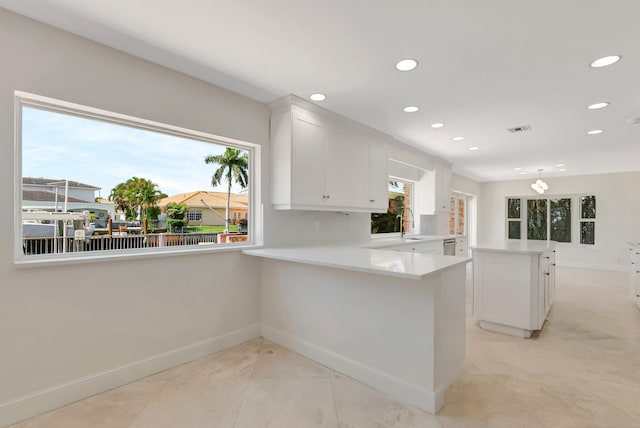kitchen featuring baseboards, recessed lighting, white cabinetry, light countertops, and a kitchen island