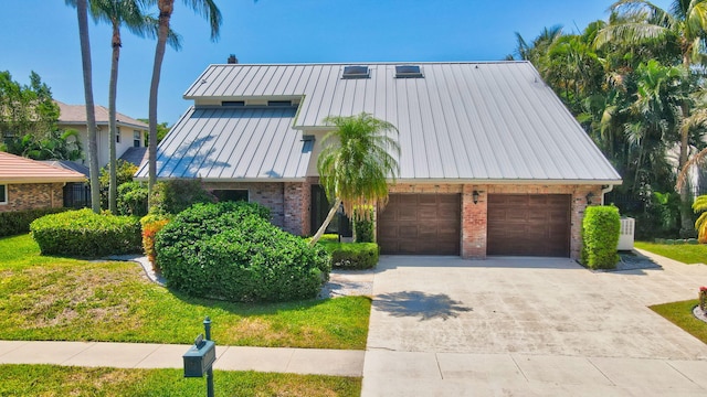 view of front of property featuring a standing seam roof, brick siding, concrete driveway, metal roof, and a garage