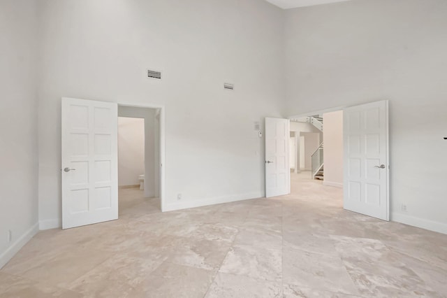 unfurnished bedroom with a high ceiling and baseboards