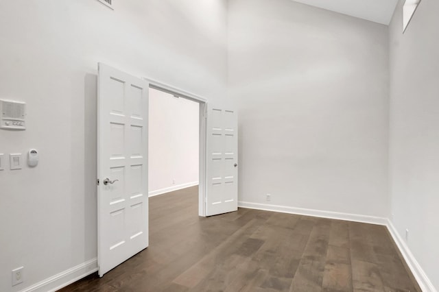 unfurnished room with dark wood-style flooring and baseboards
