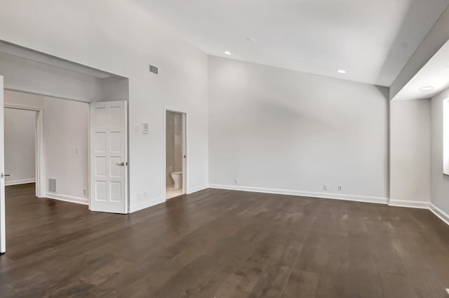 unfurnished room featuring dark wood-type flooring, baseboards, recessed lighting, and a towering ceiling