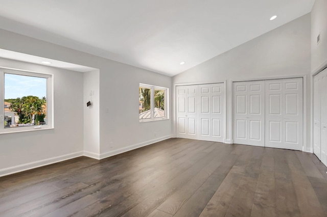 unfurnished bedroom featuring lofted ceiling, multiple closets, dark wood-style flooring, baseboards, and recessed lighting