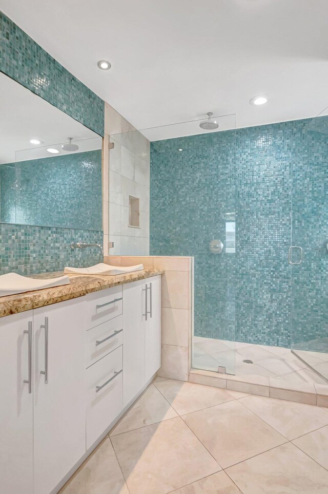 bathroom with tile walls, tile patterned floors, a stall shower, double vanity, and recessed lighting