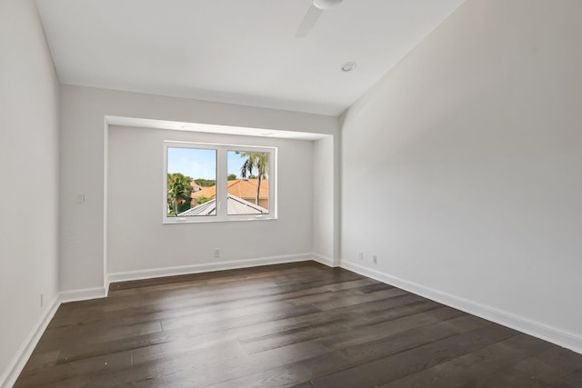 unfurnished room with dark wood-style flooring, a ceiling fan, and baseboards