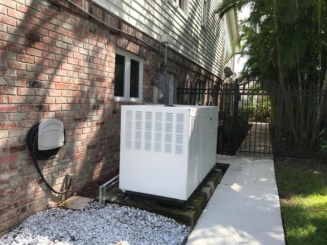 exterior view of a gate, brick siding, fence, and electric panel