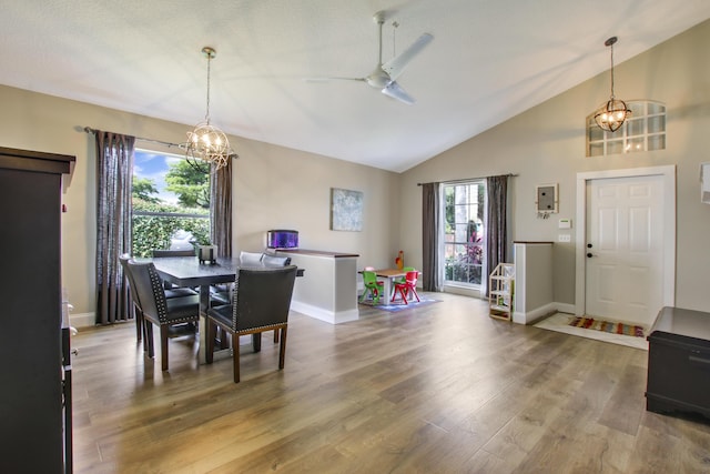 dining space featuring a chandelier, wood finished floors, baseboards, ceiling fan, and high vaulted ceiling