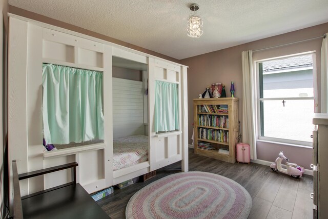 bedroom featuring a textured ceiling, wood finished floors, and baseboards
