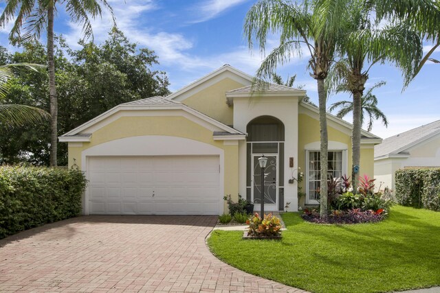 view of front of house featuring decorative driveway, an attached garage, stucco siding, and a front lawn