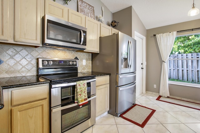 kitchen featuring appliances with stainless steel finishes, light brown cabinets, dark countertops, backsplash, and vaulted ceiling