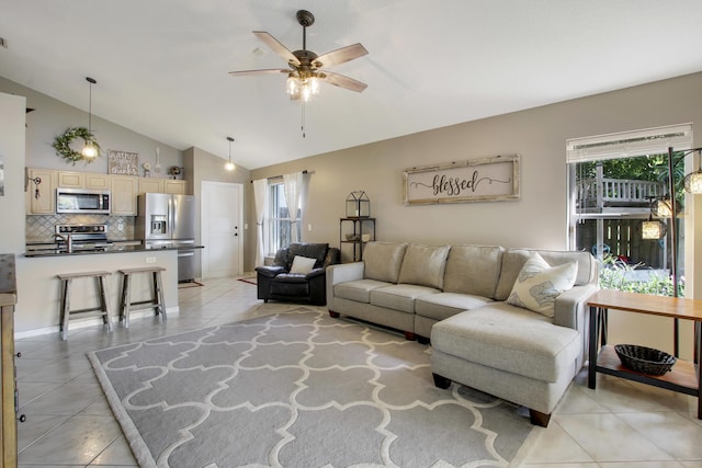 living area with vaulted ceiling, a ceiling fan, plenty of natural light, and light tile patterned floors