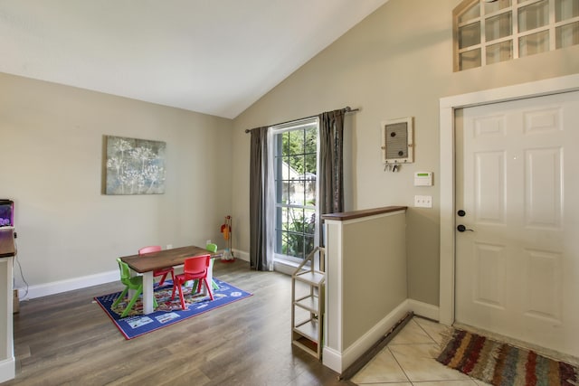 foyer entrance with baseboards, wood finished floors, and high vaulted ceiling