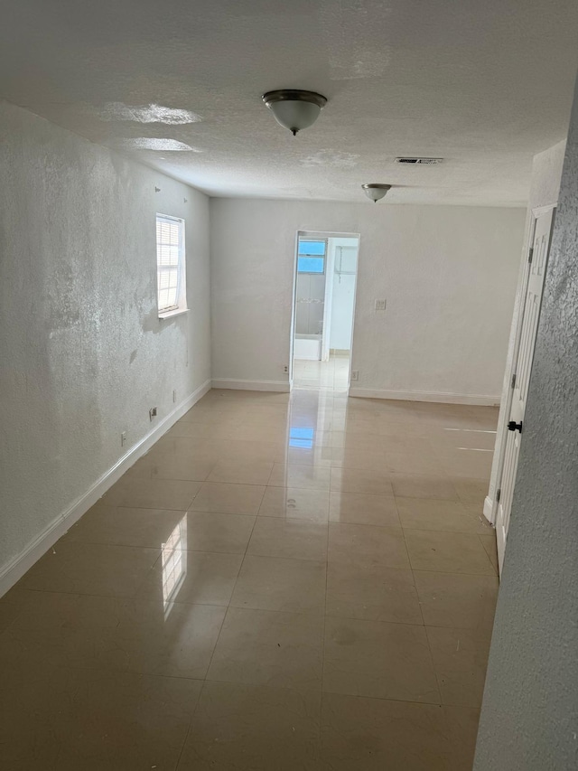 4420 NW 34th St, Lauderdale Lakes, FL 33319 - spare room with baseboards, light tile patterned flooring, a textured ceiling, and a textured wall