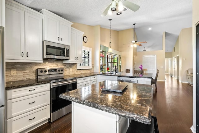 kitchen featuring stainless steel appliances, ceiling fan, a peninsula, backsplash, and white cabinets