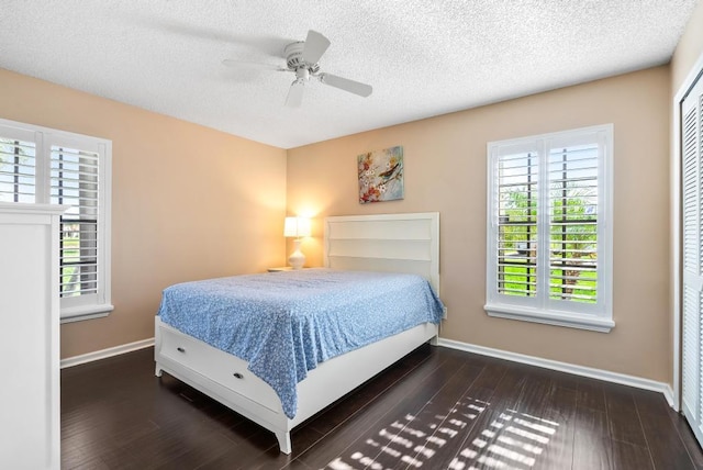 bedroom featuring multiple windows, baseboards, wood finished floors, a textured ceiling, and ceiling fan
