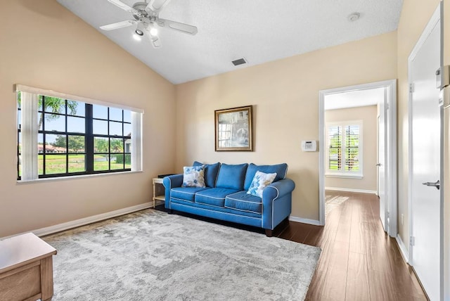 living room with dark wood-type flooring, a ceiling fan, lofted ceiling, and baseboards