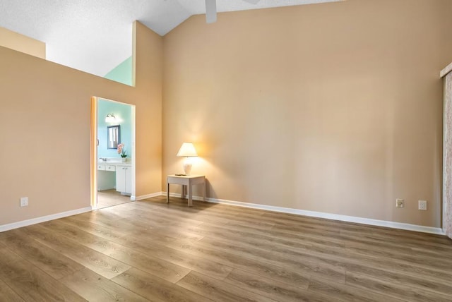 spare room featuring wood finished floors, high vaulted ceiling, baseboards, and a ceiling fan
