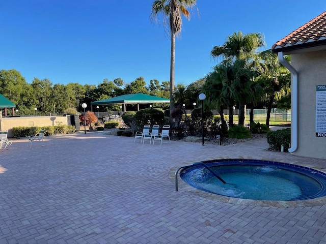 view of pool with fence, a hot tub, and a patio