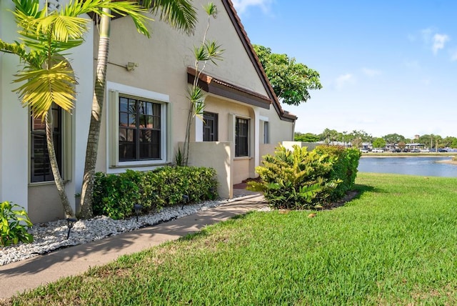 view of property exterior featuring a yard, stucco siding, and a water view