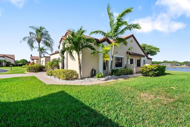 view of property exterior featuring stucco siding, a lawn, and a water view