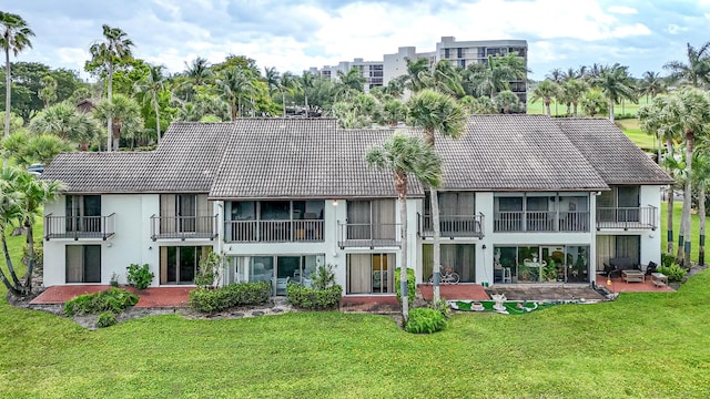 5218 Fountains Dr S Unit 206, Lake Worth, FL 33467 - rear view of property featuring a tile roof, a patio, a lawn, and stucco siding
