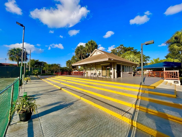 view of parking featuring fence and a tennis court