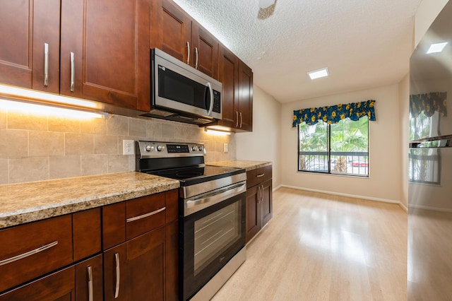 10173 Mangrove Dr Unit 204, Boynton Beach, FL 33437 - kitchen with stainless steel appliances, baseboards, backsplash, light wood-style flooring, and a textured ceiling