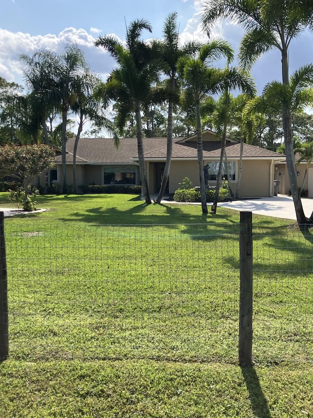 view of front of home featuring a front yard, concrete driveway, a garage, and stucco siding