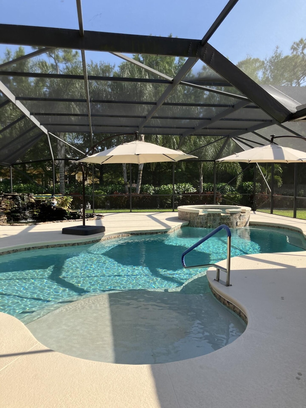 view of pool with a patio area, a pool with connected hot tub, and glass enclosure