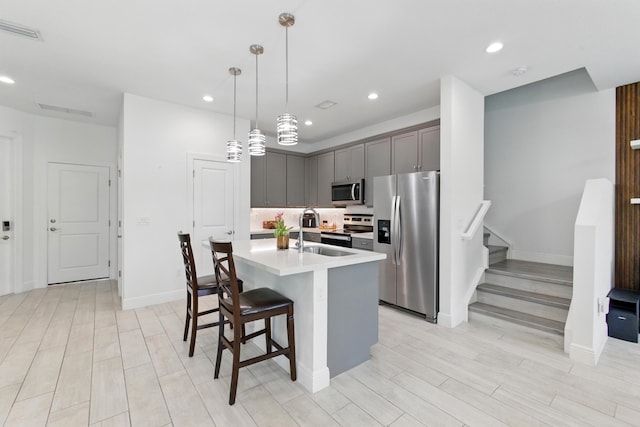 622 Parsons Way, Deerfield Beach, FL 33442 - kitchen with stainless steel appliances, light countertops, an island with sink, a sink, and light wood finished floors