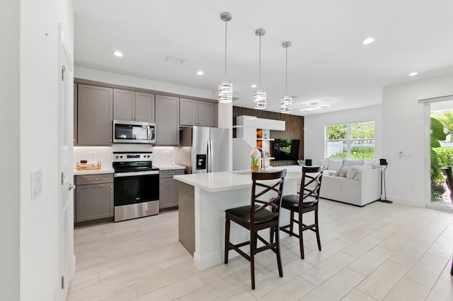 622 Parsons Way, Deerfield Beach, FL 33442 - kitchen featuring appliances with stainless steel finishes, gray cabinetry, light countertops, open floor plan, and decorative backsplash
