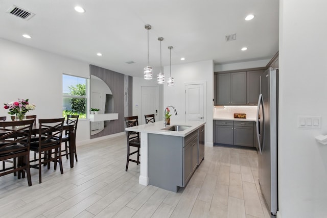 622 Parsons Way, Deerfield Beach, FL 33442 - kitchen featuring a sink, stainless steel appliances, gray cabinetry, light wood-style flooring, and an island with sink