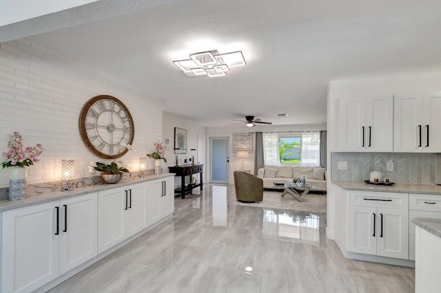 kitchen featuring decorative backsplash, light countertops, white cabinetry, and a ceiling fan
