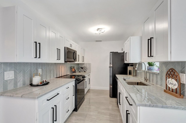 kitchen with black range with electric stovetop, a sink, backsplash, white cabinetry, and baseboards