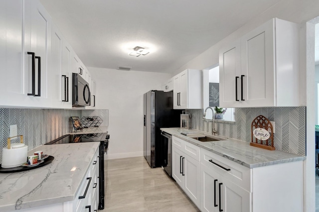 kitchen with black appliances, a sink, baseboards, backsplash, and white cabinetry