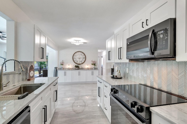 kitchen featuring black appliances, a sink, tasteful backsplash, and white cabinetry