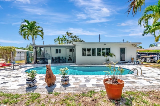 outdoor pool featuring a sunroom, a patio, and fence