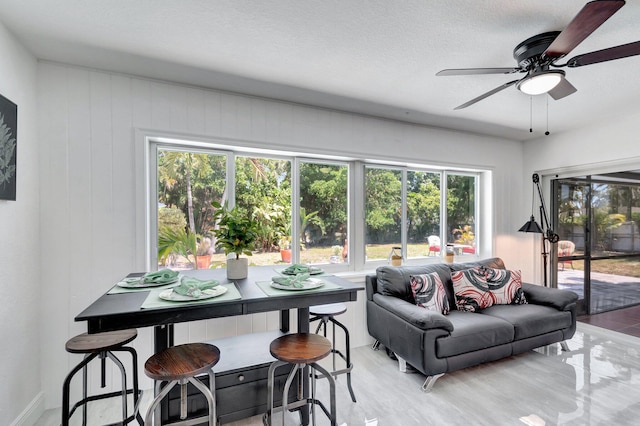 living area featuring plenty of natural light, a ceiling fan, and light wood-style floors