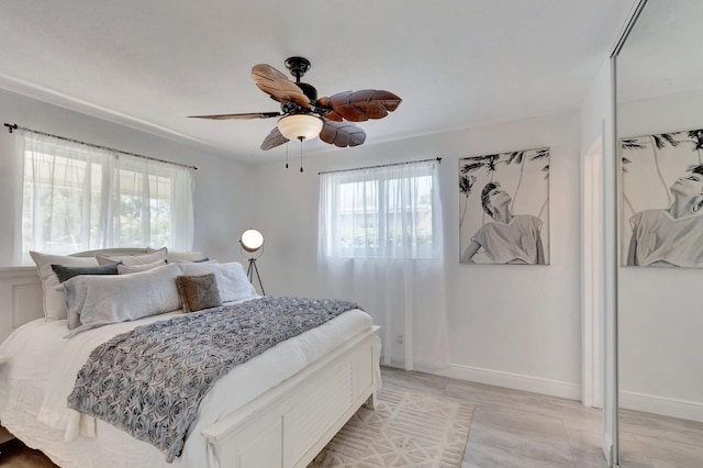 bedroom with multiple windows, a ceiling fan, and baseboards