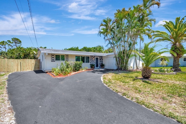 ranch-style home with a garage, fence, driveway, and stucco siding