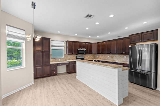 9226 Dupont Pl, Wellington, FL 33414 - kitchen with stainless steel appliances, tasteful backsplash, dark brown cabinetry, light wood-style floors, and an island with sink