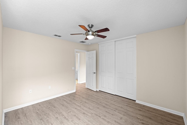 9226 Dupont Pl, Wellington, FL 33414 - unfurnished bedroom with wood finished floors, baseboards, a closet, a ceiling fan, and a textured ceiling
