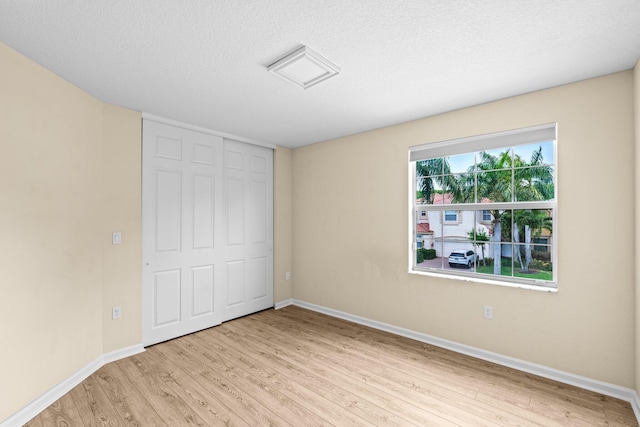 9226 Dupont Pl, Wellington, FL 33414 - unfurnished bedroom featuring light wood-type flooring, baseboards, a textured ceiling, and a closet
