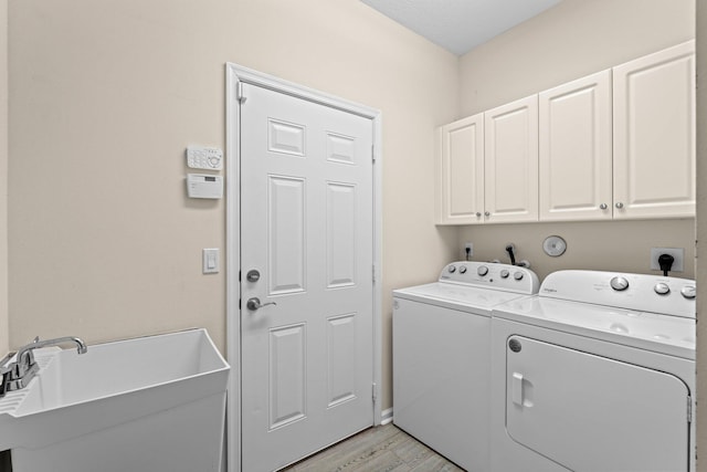 9226 Dupont Pl, Wellington, FL 33414 - laundry area featuring washing machine and clothes dryer, cabinet space, and light wood-type flooring
