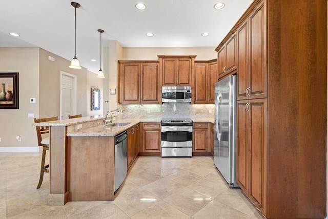 10887 Summerville Way, Boynton Beach, FL 33437 - kitchen featuring stainless steel appliances, a sink, brown cabinets, a peninsula, and a breakfast bar area