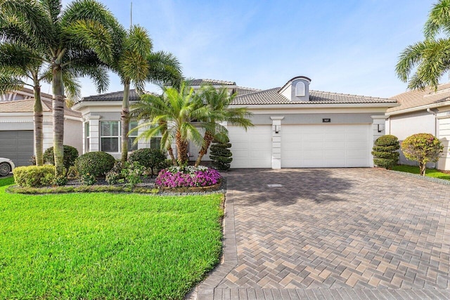 9037 Golden Mountain Cir, Boynton Beach, FL 33473 - mediterranean / spanish house with decorative driveway, stucco siding, an attached garage, a front lawn, and a tiled roof