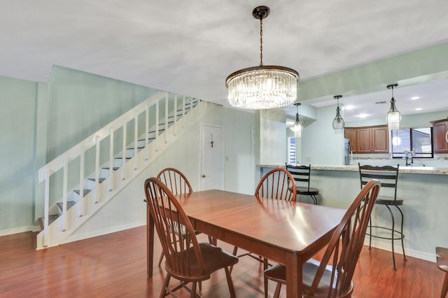 dining area with stairway, wood finished floors, a chandelier, and baseboards
