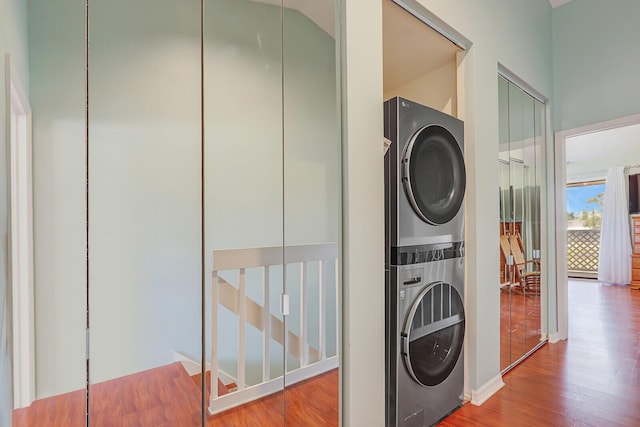 clothes washing area featuring stacked washer and clothes dryer and wood finished floors