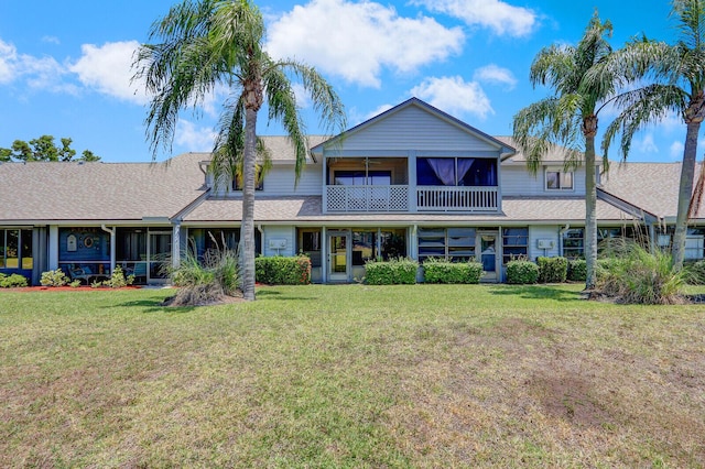 view of front of home with a front yard, a sunroom, and roof with shingles
