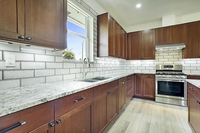 2510 Lake Dr N, Boynton Beach, FL 33435 - kitchen featuring stainless steel range with gas stovetop, under cabinet range hood, a sink, light stone counters, and decorative backsplash