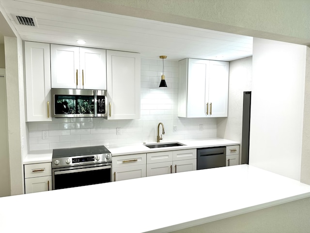 kitchen featuring appliances with stainless steel finishes, a sink, backsplash, white cabinets, and light countertops